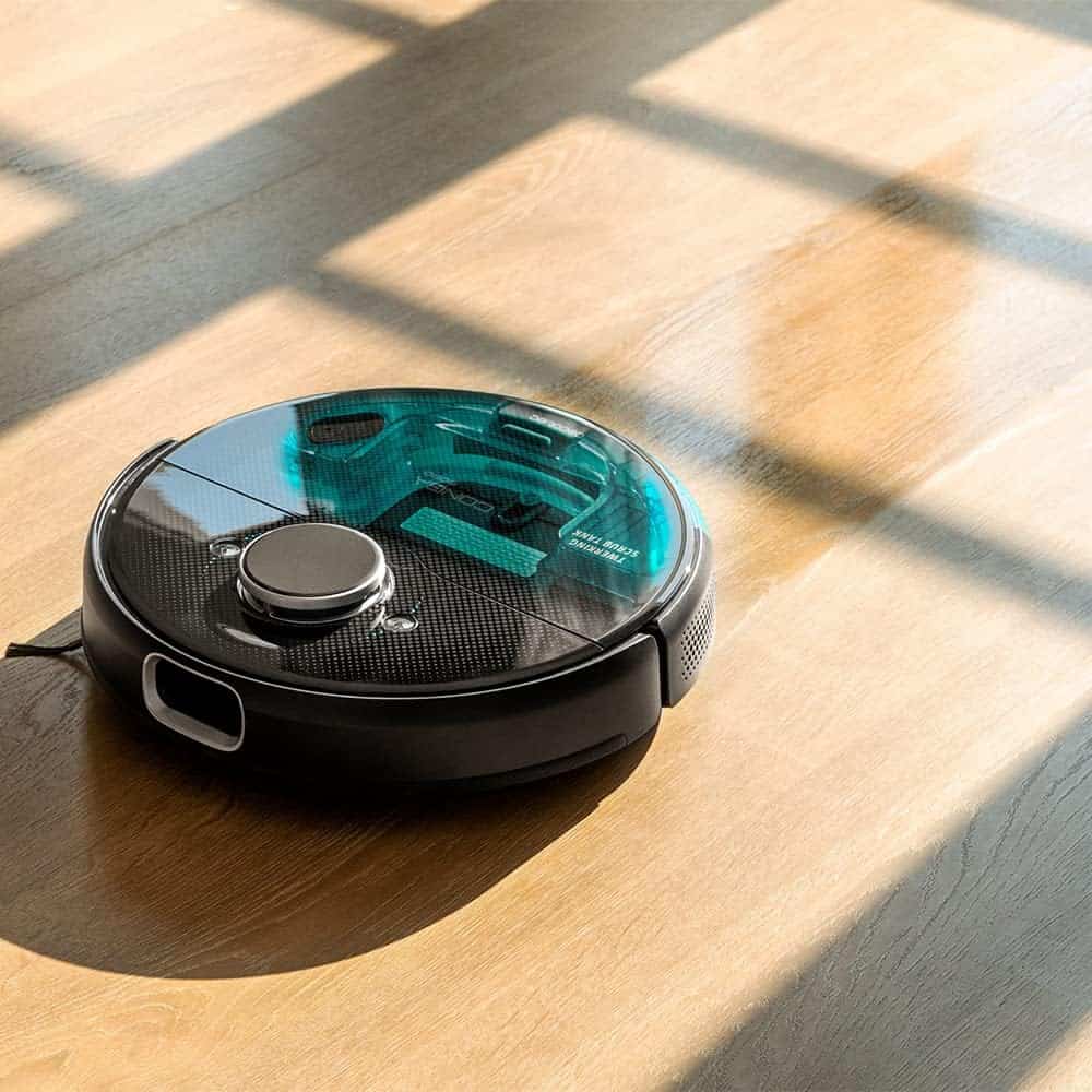 Un robot aspirateur assis sur un plancher en bois.