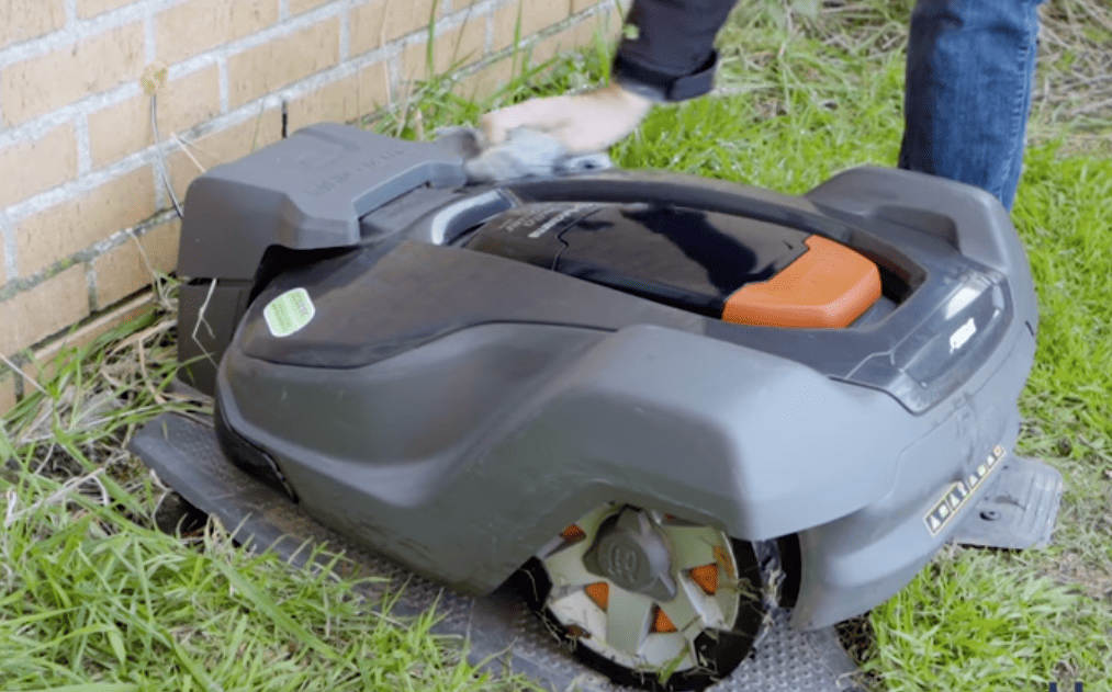 Une personne utilisant un robot tondeuse à gazon pour tondre une pelouse.