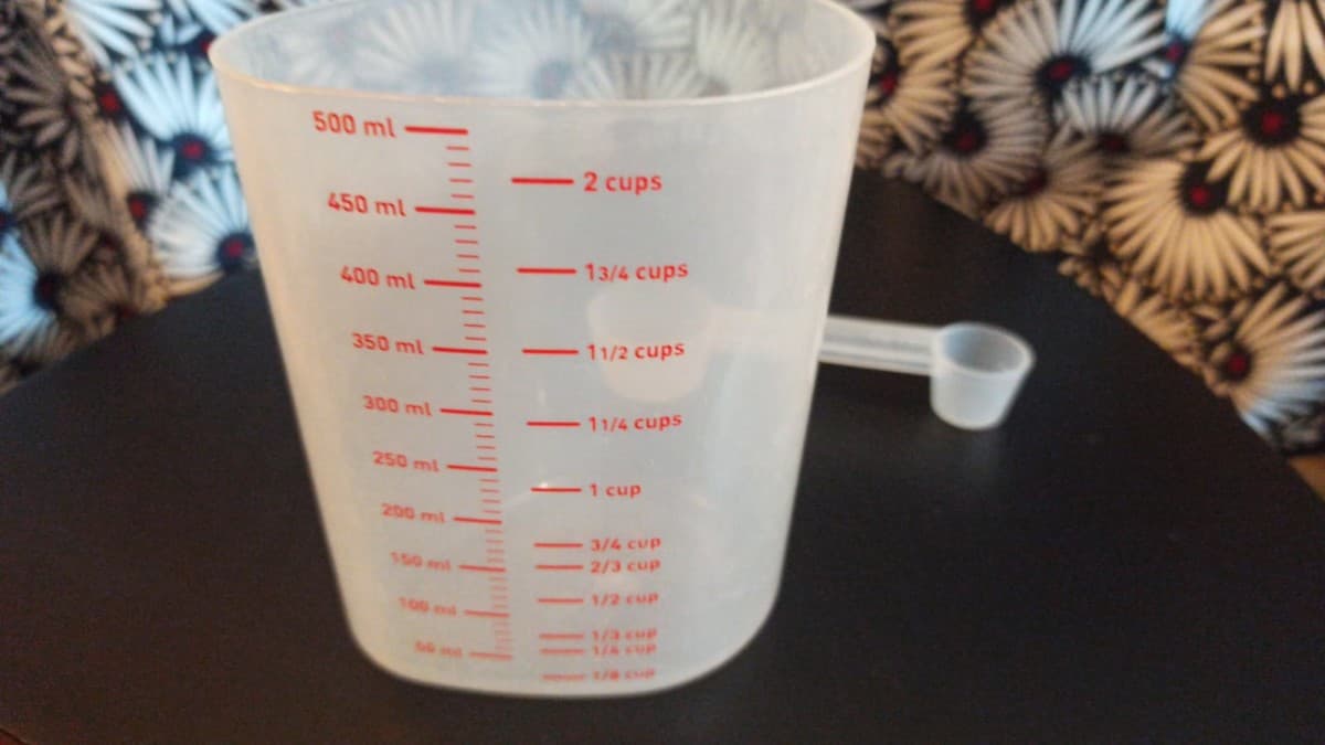 Une tasse à mesurer en plastique est posée sur une table.