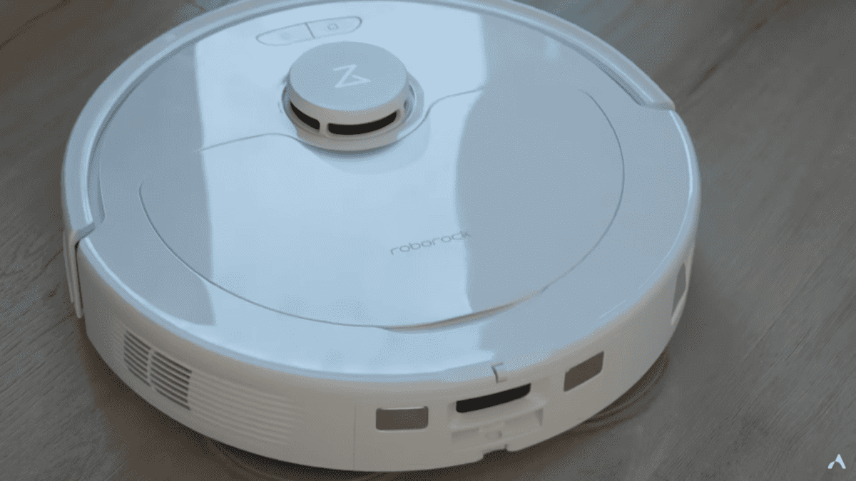 Un robot aspirateur blanc posé sur un parquet.