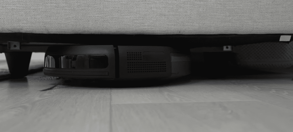 Un robot sous un canapé dans un salon.