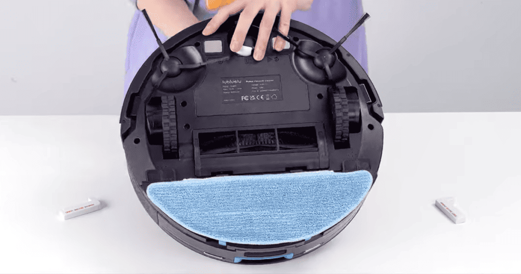 Une personne utilisant un chiffon bleu pour nettoyer l’intérieur d’un aspirateur.